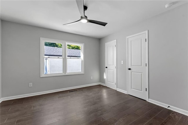 unfurnished bedroom featuring dark wood-type flooring, visible vents, ceiling fan, and baseboards