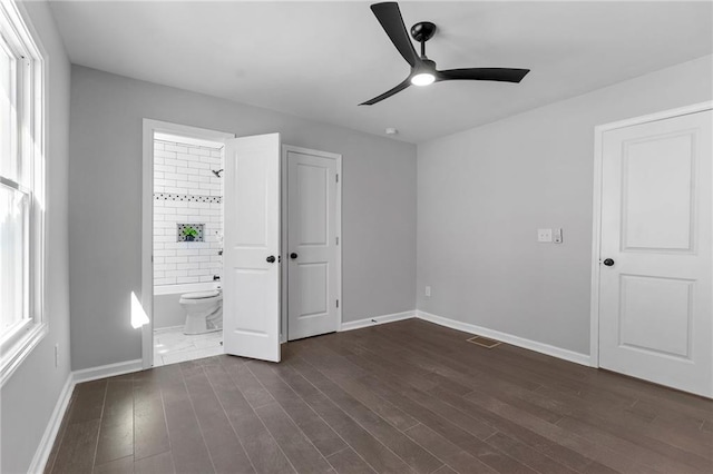 unfurnished bedroom featuring ensuite bathroom, dark wood-type flooring, visible vents, and baseboards