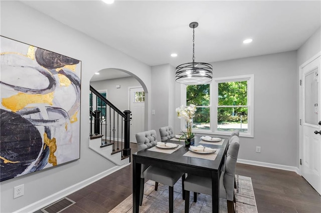 dining room featuring stairway, dark wood-style flooring, visible vents, and baseboards