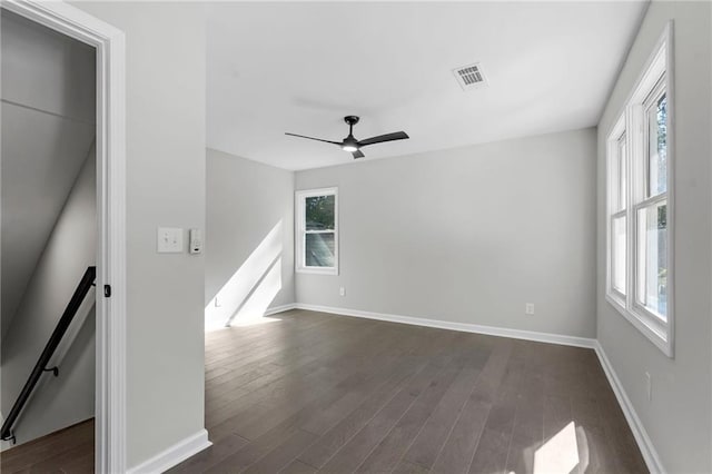 spare room with visible vents, baseboards, and dark wood-style flooring