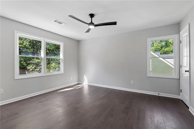 empty room featuring baseboards, plenty of natural light, visible vents, and dark wood-style flooring