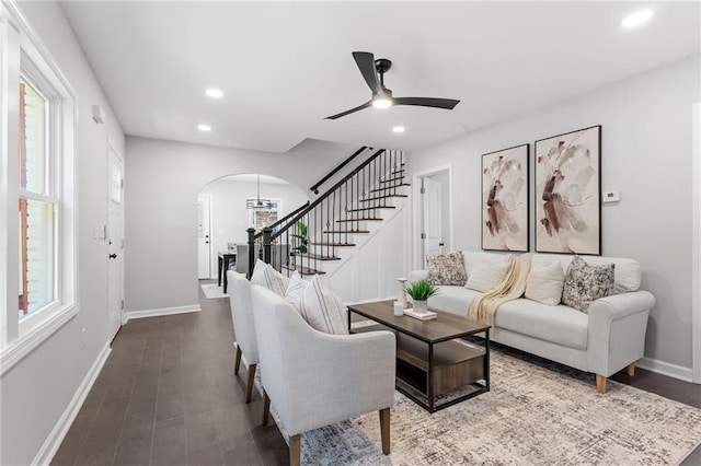 living area featuring arched walkways, stairway, wood finished floors, and a wealth of natural light