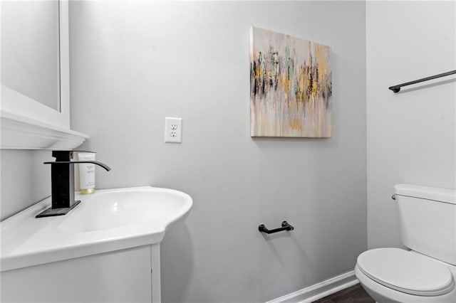 half bath with vanity, toilet, and baseboards