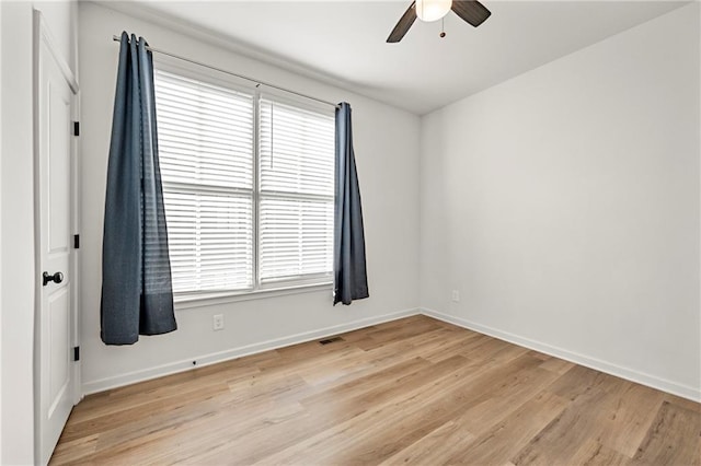 empty room featuring ceiling fan, a healthy amount of sunlight, and light wood-type flooring