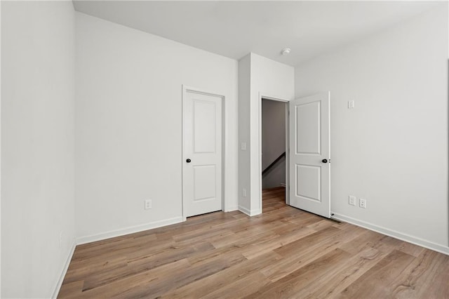 unfurnished bedroom with baseboards and light wood-type flooring