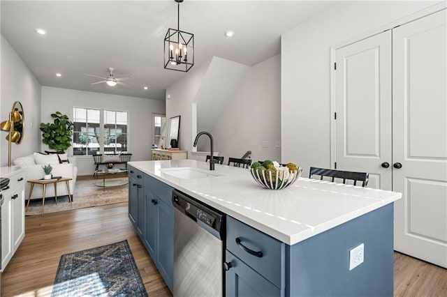 kitchen featuring blue cabinets, light wood-type flooring, dishwasher, and a sink