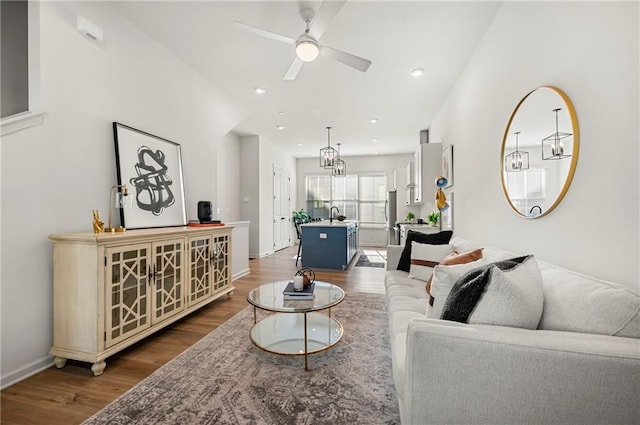 living area featuring recessed lighting, baseboards, dark wood finished floors, and ceiling fan with notable chandelier