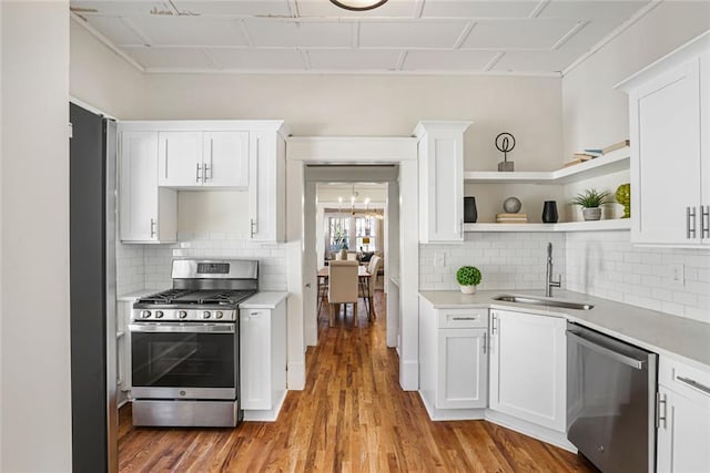 kitchen with open shelves, stainless steel appliances, light countertops, white cabinets, and a sink