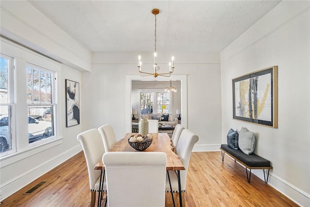 dining space with a chandelier, light wood-style flooring, visible vents, and baseboards