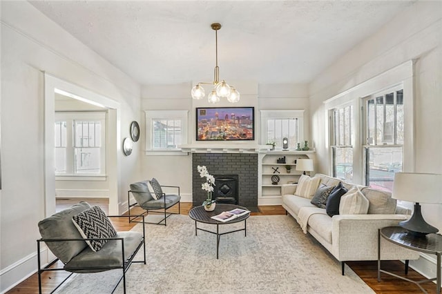 living area featuring a chandelier, a fireplace, wood finished floors, and baseboards