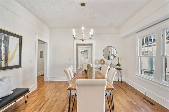 dining space with visible vents, a notable chandelier, light wood-style flooring, and baseboards