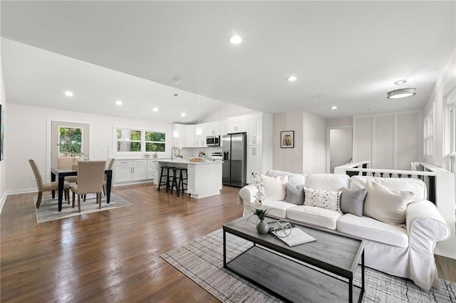 living room featuring vaulted ceiling, dark wood-type flooring, and sink