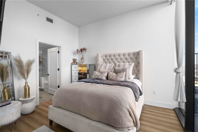 bedroom featuring baseboards, visible vents, and wood finished floors