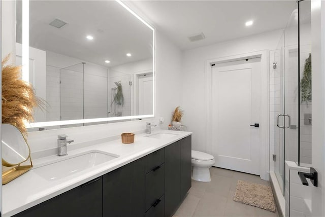 full bath featuring double vanity, a sink, toilet, and a shower stall