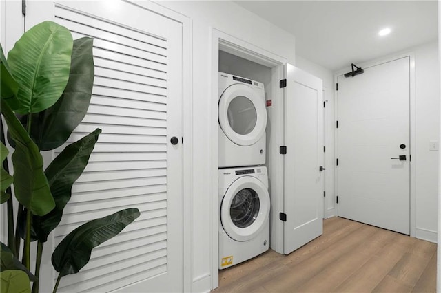 laundry room with recessed lighting, laundry area, light wood-type flooring, and stacked washer / dryer