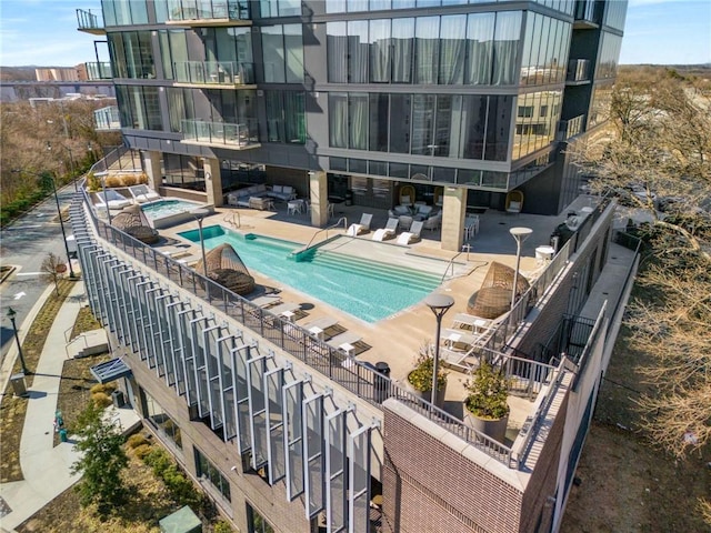 community pool featuring a patio, a hot tub, and stairway