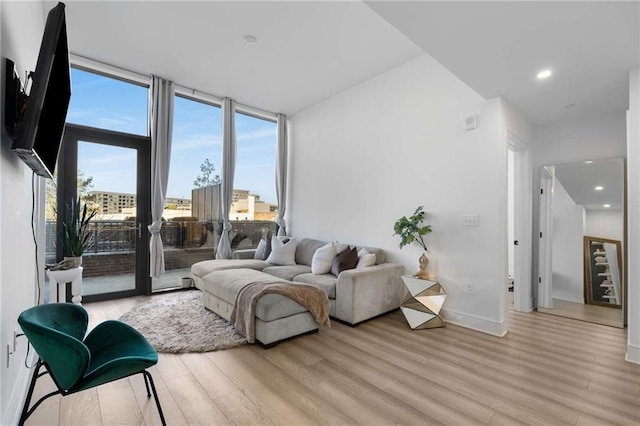 living area with recessed lighting, a wall of windows, baseboards, and light wood-style floors