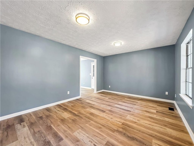 empty room featuring a textured ceiling and light hardwood / wood-style flooring