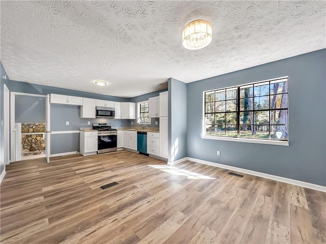 kitchen with light hardwood / wood-style floors, stainless steel appliances, a textured ceiling, sink, and white cabinetry