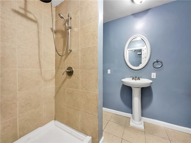 bathroom with tile patterned flooring, a tile shower, and sink