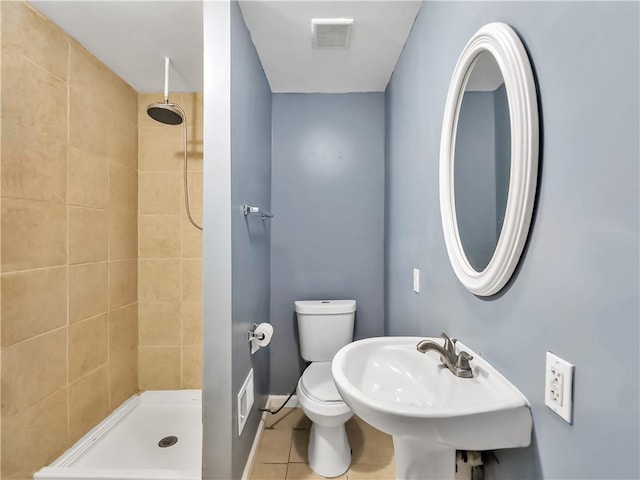 bathroom featuring sink, tile patterned flooring, a tile shower, and toilet