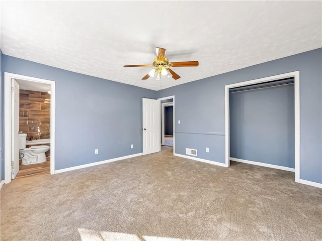 unfurnished bedroom with connected bathroom, carpet floors, ceiling fan, and a textured ceiling