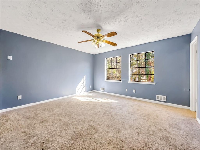 carpeted spare room with a textured ceiling and ceiling fan