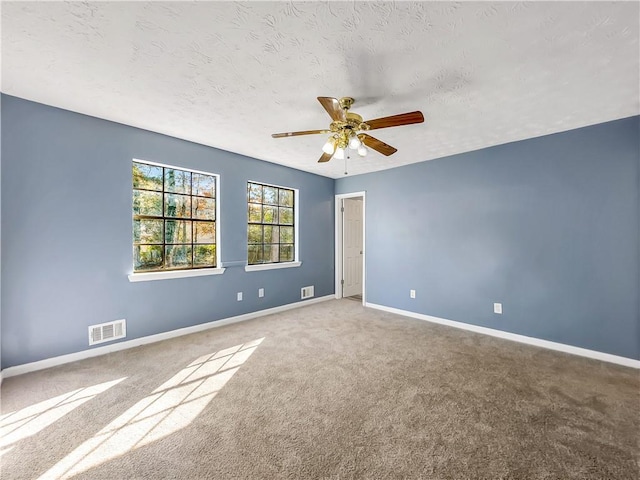 carpeted spare room featuring ceiling fan and a textured ceiling