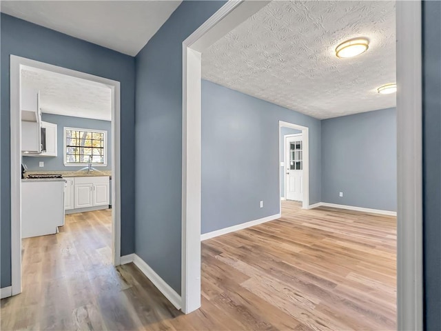 hall featuring sink, a textured ceiling, and light wood-type flooring