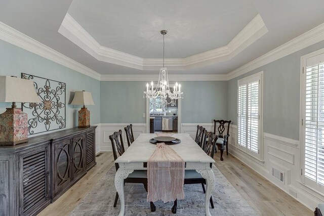 2623 Lindsey Grace Ln, Buford, GA 30519 - dining room featuring a raised ceiling, a chandelier, wainscoting, light wood-style floors, and ornamental molding
