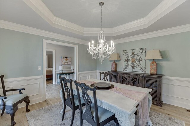 2623 Lindsey Grace Ln, Buford, GA 30519 - dining room featuring a tray ceiling, a decorative wall, light wood-style floors, a wainscoted wall, and a chandelier