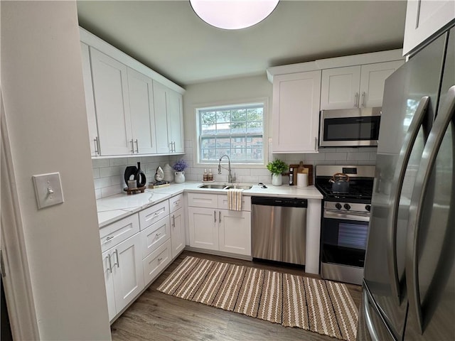 kitchen with white cabinetry, sink, stainless steel appliances, dark hardwood / wood-style flooring, and decorative backsplash