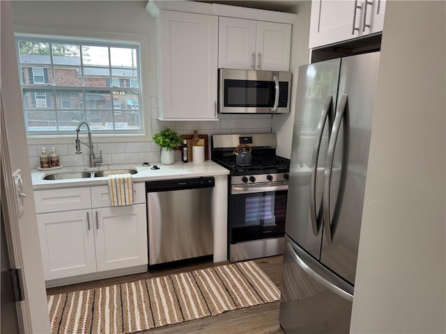 kitchen featuring white cabinets, stainless steel appliances, tasteful backsplash, and sink