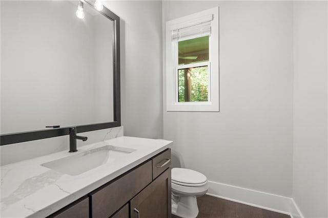 bathroom with toilet, baseboards, wood finished floors, and vanity