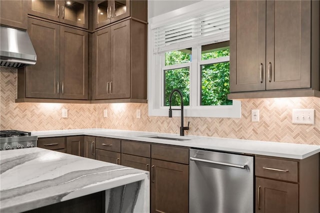 kitchen with decorative backsplash, dishwasher, glass insert cabinets, a sink, and exhaust hood