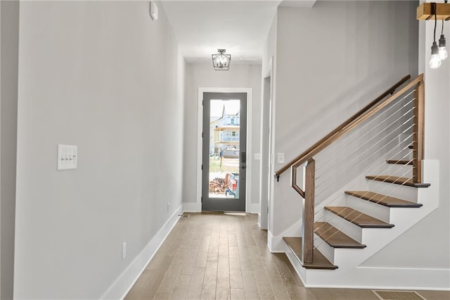 foyer with stairs, baseboards, and wood finished floors