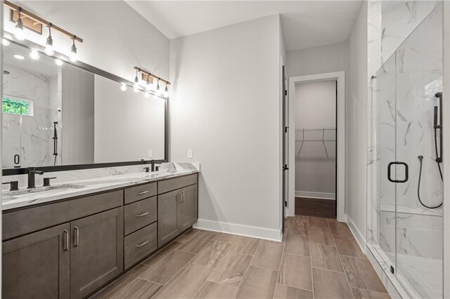 bathroom with a sink, a marble finish shower, and baseboards