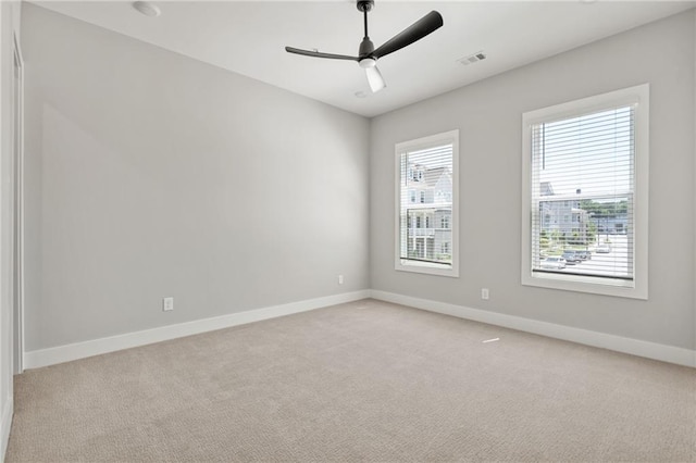 spare room with ceiling fan, visible vents, baseboards, and light colored carpet