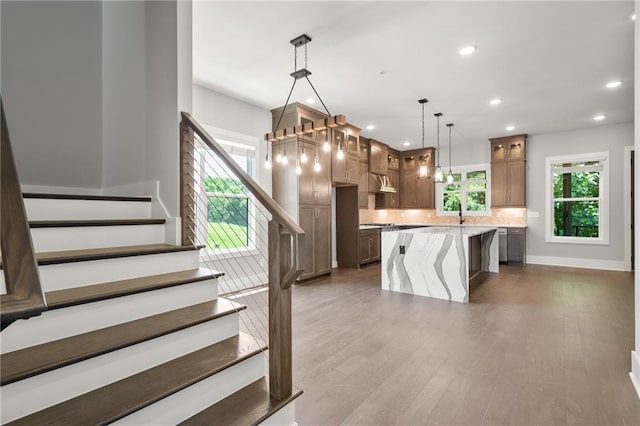 kitchen featuring recessed lighting, decorative backsplash, glass insert cabinets, a kitchen island, and wood finished floors