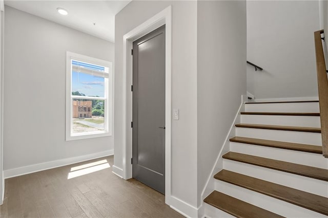 staircase with baseboards, wood finished floors, and recessed lighting