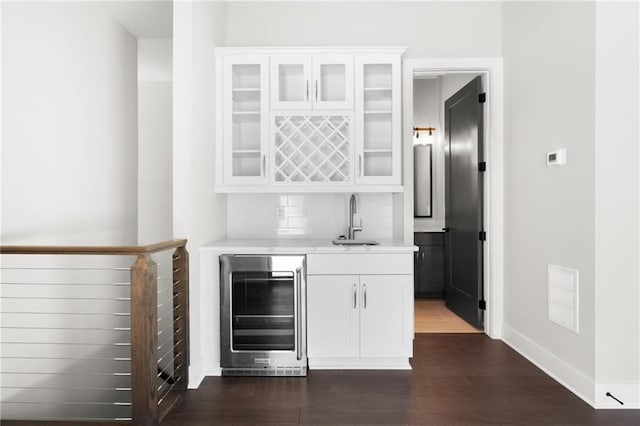 bar with indoor wet bar, visible vents, dark wood-type flooring, a sink, and beverage cooler