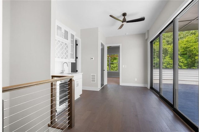 interior space with indoor wet bar, visible vents, dark wood-type flooring, beverage cooler, and baseboards