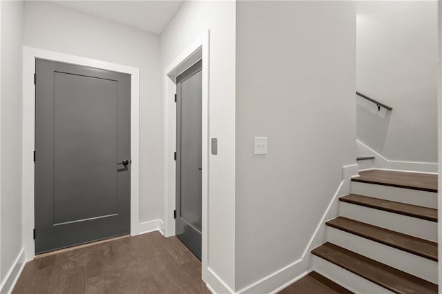 entrance foyer featuring dark wood-style flooring, stairway, and baseboards