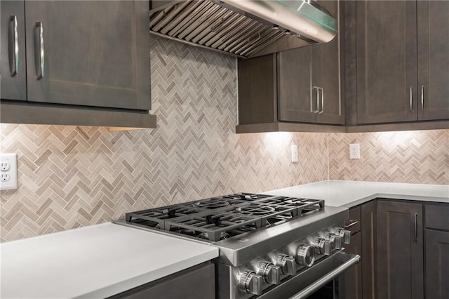 kitchen featuring light countertops, high end stainless steel range oven, decorative backsplash, dark brown cabinets, and wall chimney exhaust hood