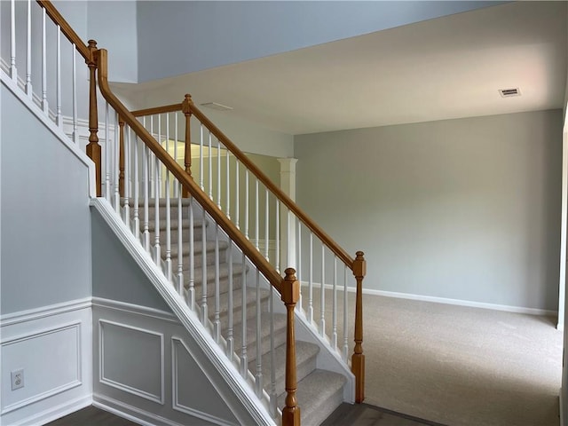 staircase with a wainscoted wall, carpet floors, and baseboards