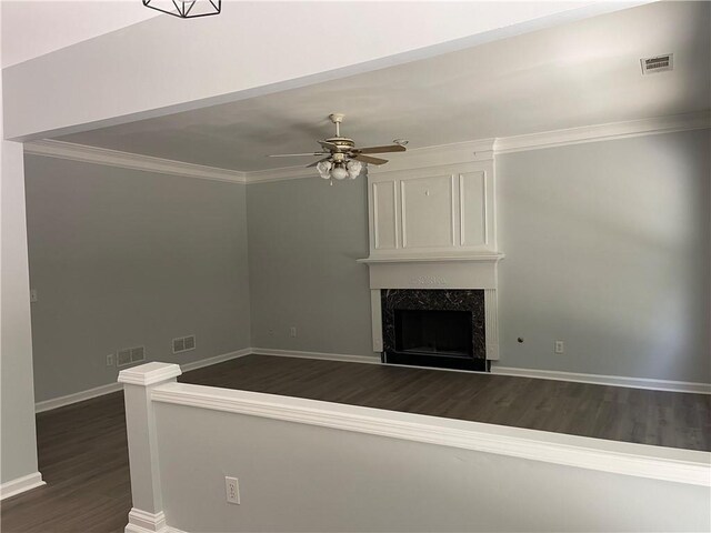 unfurnished living room with dark wood finished floors, a high end fireplace, a ceiling fan, baseboards, and ornamental molding