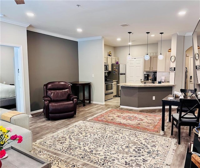 living room featuring ornamental molding, light wood finished floors, baseboards, recessed lighting, and arched walkways
