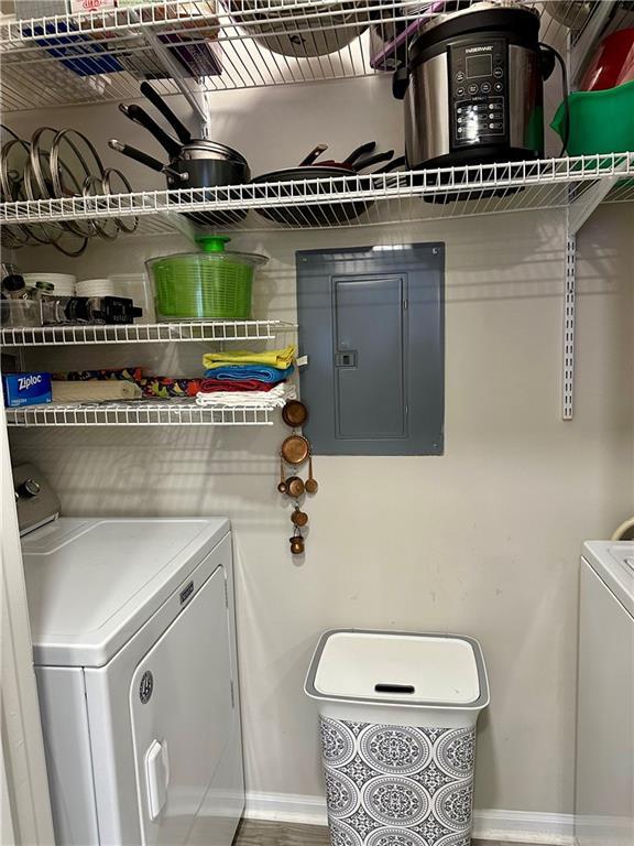 laundry room with electric panel, washer and dryer, and baseboards