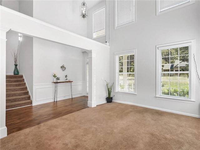 foyer entrance featuring a towering ceiling, stairs, a chandelier, and carpet flooring