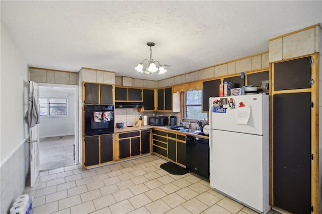 kitchen featuring an inviting chandelier, under cabinet range hood, a textured ceiling, black appliances, and a sink